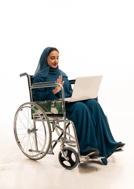 امرأة إماراتية على كرسي متحرك تستخدم كمبيوتر محمول