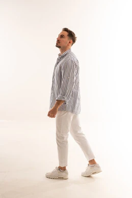 رجل سعودي يمشي على خلفية استوديو بيضاء وينظر للأعلى