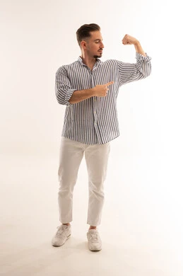 رجل سعودي يثني عضلات ذراعه في خلفية استوديو بيضاء