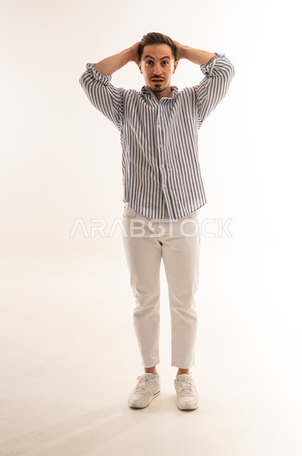 رجل سعودي مصدوم يضع يديه على رأسه في الاستوديو