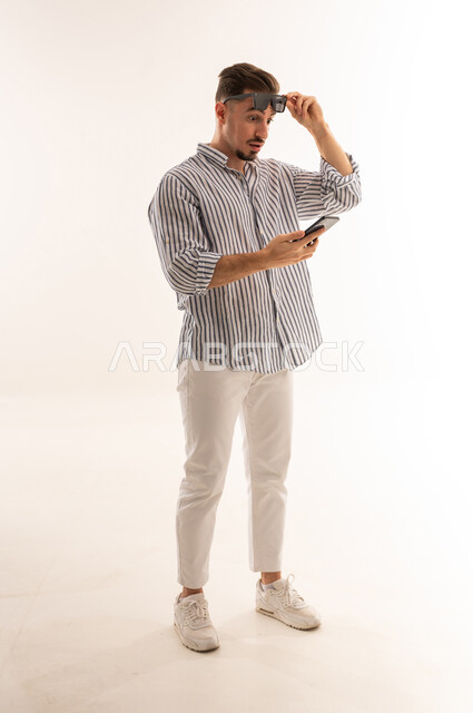 Surprised Saudi Man Looking at Smartphone in Studio