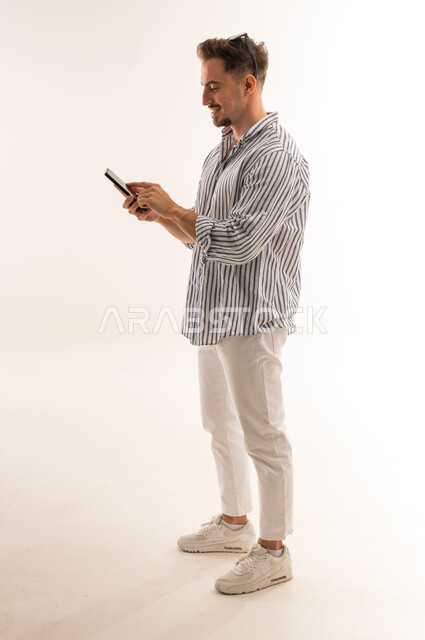 رجل سعودي يستخدم الهاتف الذكي بخلفية بيضاء