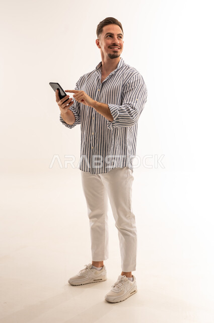 Saudi Man Using Smartphone on Plain White Studio Background
