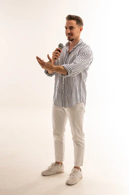 رجل سعودي يقدم عرضاً بميكروفون في استوديو أبيض