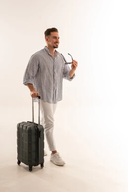 رجل سعودي يسير بحقيبة سفر سوداء بخلفية بيضاء
