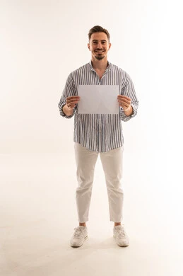 رجل سعودي يحمل ورقة بيضاء فارغة في الاستوديو