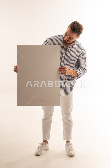 رجل سعودي يحمل لوحة بيضاء فارغة تصوير استوديو