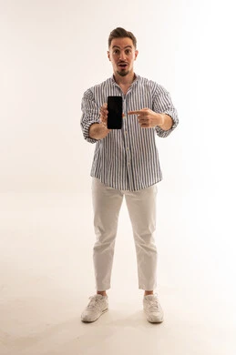 رجل سعودي يشير إلى هاتف ذكي على خلفية بيضاء