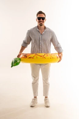 رجل سعودي يحمل عوامة مسبح صيفية على خلفية بيضاء