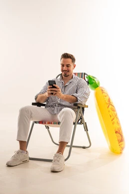 رجل سعودي يحمل هاتفاً ذكياً مع عوامة مسبح أناناس