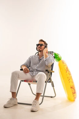 رجل سعودي على كرسي شاطئ مع معدات عطلة الصيف