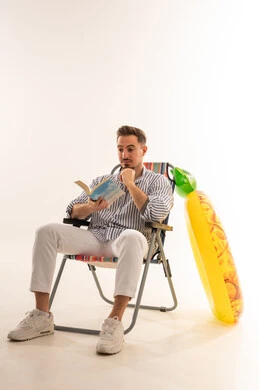 رجل سعودي يقرأ كتاباً على كرسي بحر مع عوامة أناناس