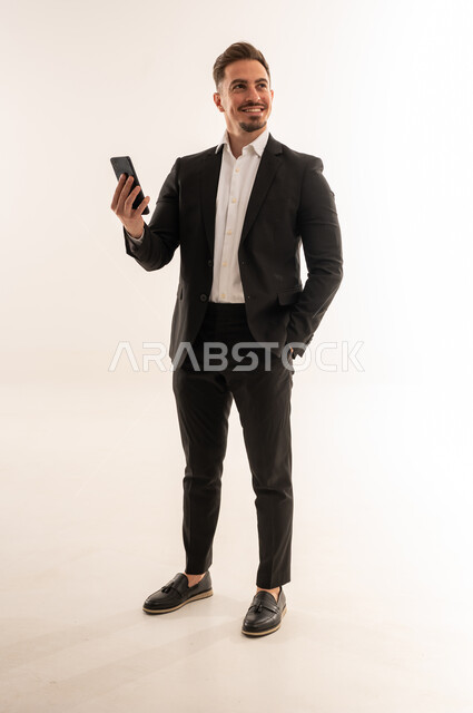 رجل أعمال سعودي مع هاتف ذكي في استوديو أبيض