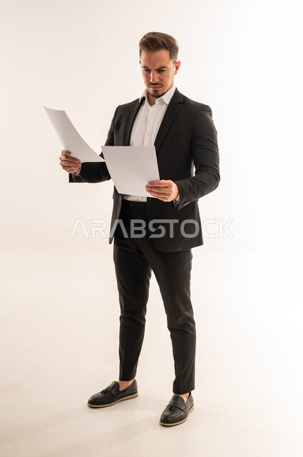 رجل أعمال سعودي يراجع مستندات على خلفية بيضاء