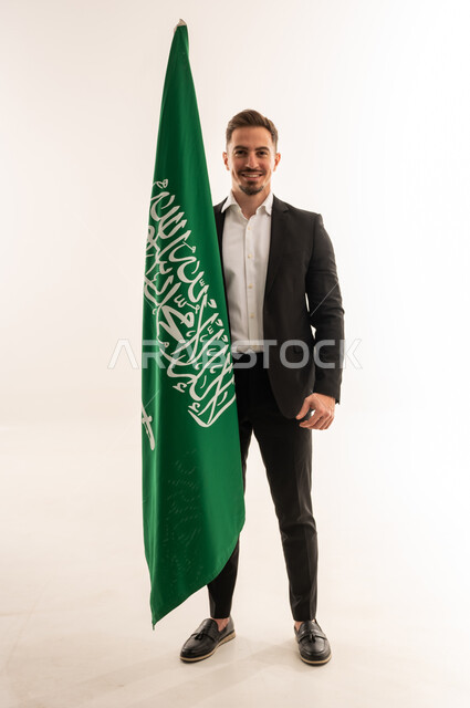 رجل سعودي ببدلة رسمية مع علم السعودية
