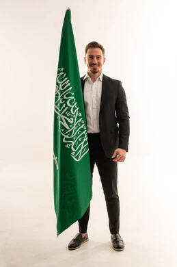 رجل سعودي ببدلة رسمية مع علم السعودية