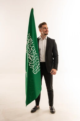 Saudi Man in Suit Standing Beside the Saudi National Flag