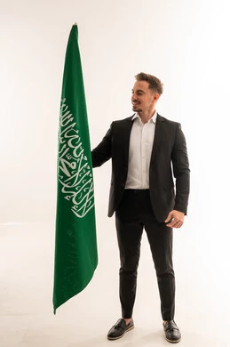 رجل سعودي بالبدلة الرسمية يمسك العلم السعودي