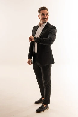 رجل أعمال سعودي يرتدي بدلة رسمية سوداء وينظر للساعة