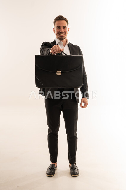 رجل أعمال سعودي يحمل حقيبة عمل على خلفية بيضاء