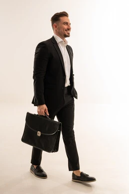 رجل أعمال سعودي يمشي مع حقيبة ببدلة رسمية سوداء