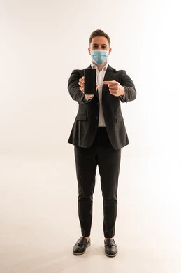 رجل أعمال سعودي يرتدي كمامة ويشير لهاتف ذكي