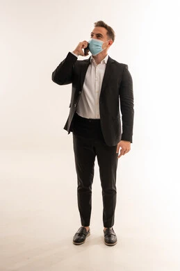 رجل أعمال سعودي ببدلة رسمية وكمامة يتحدث بالهاتف