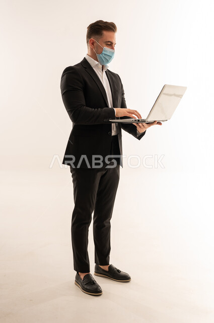 رجل أعمال سعودي بالكمامة يستخدم اللابتوب خلفية بيضاء