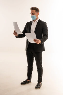 رجل أعمال سعودي يرتدي كمامة ويمسك أوراقاً