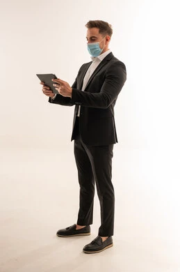 رجل أعمال سعودي يرتدي بدلة وكمامة مع جهاز لوحي