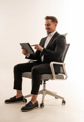 رجل أعمال سعودي يجلس مع جهاز لوحي بخلفية بيضاء