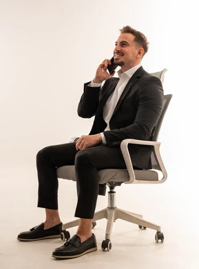 رجل أعمال سعودي يتحدث عبر الهاتف الذكي جالسًا على كرسي