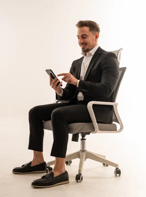 رجل أعمال سعودي ببدلة رسمية يستخدم الهاتف الذكي