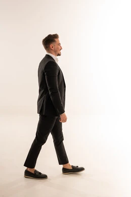 رجل أعمال سعودي يمشي ببدلة رسمية على خلفية بيضاء