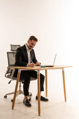 Saudi Businessman Writing at Desk with Laptop