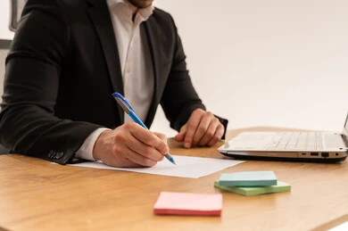 رجل أعمال سعودي يكتب على مكتب عمل مع لابتوب