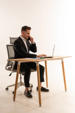 رجل أعمال سعودي على مكتب يستخدم لابتوب وهاتف