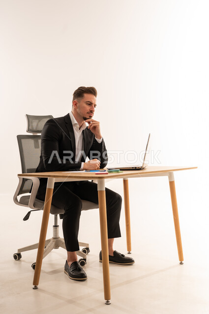 رجل أعمال سعودي يجلس على مكتب مع لابتوب