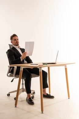 رجل أعمال سعودي يقرأ وثيقة على مكتب مع لابتوب