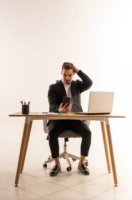 رجل أعمال سعودي جالس على مكتبه مع هاتف ذكي