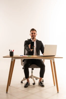 رجل أعمال سعودي يعرض هاتفاً ذكياً على المكتب