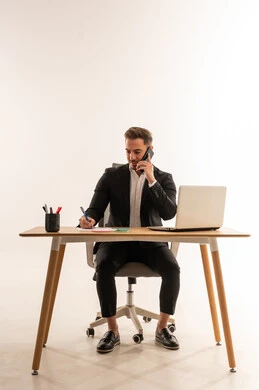 رجل أعمال سعودي يكتب على مكتبه بخلفية بيضاء