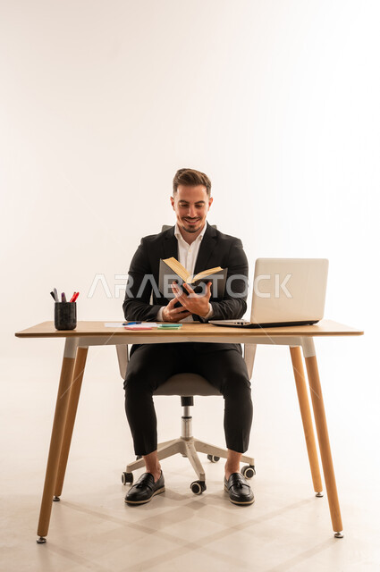 رجل أعمال سعودي يقرأ كتاباً في مكتبه