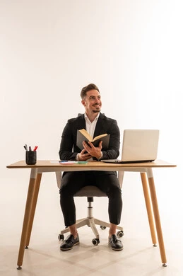 رجل أعمال سعودي يقرأ كتاباً على مكتب بخلفية بيضاء