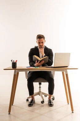 رجل أعمال سعودي يقرأ كتاباً على مكتبه في الاستوديو