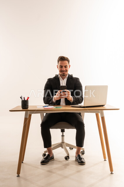 رجل أعمال سعودي يستخدم الهاتف الذكي في المكتب