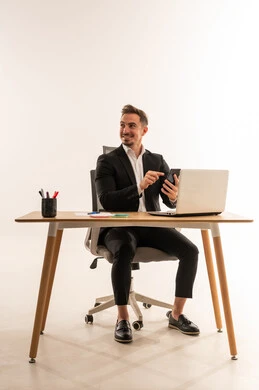 رجل أعمال سعودي يستخدم الهاتف الذكي على مكتب العمل