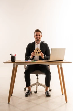 Saudi Businessman Holding House Model at Office Desk