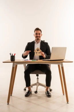 رجل أعمال سعودي مع مجسم منزل على مكتب