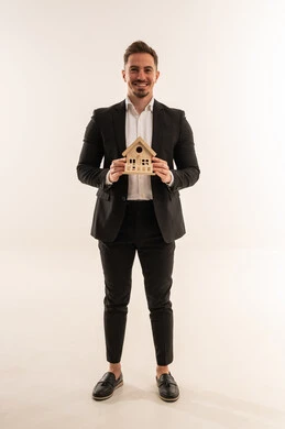 رجل أعمال سعودي يمسك نموذج منزل على خلفية بيضاء